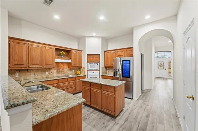 a kitchen with stainless steel appliances granite countertop wooden cabinets and sink