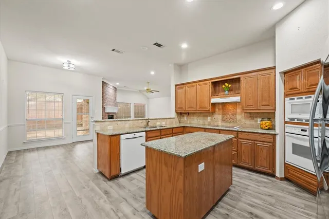 a kitchen with stainless steel appliances granite countertop refrigerator a sink a stove and wooden floor