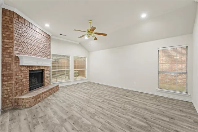 a view of an empty room with a fireplace and a window