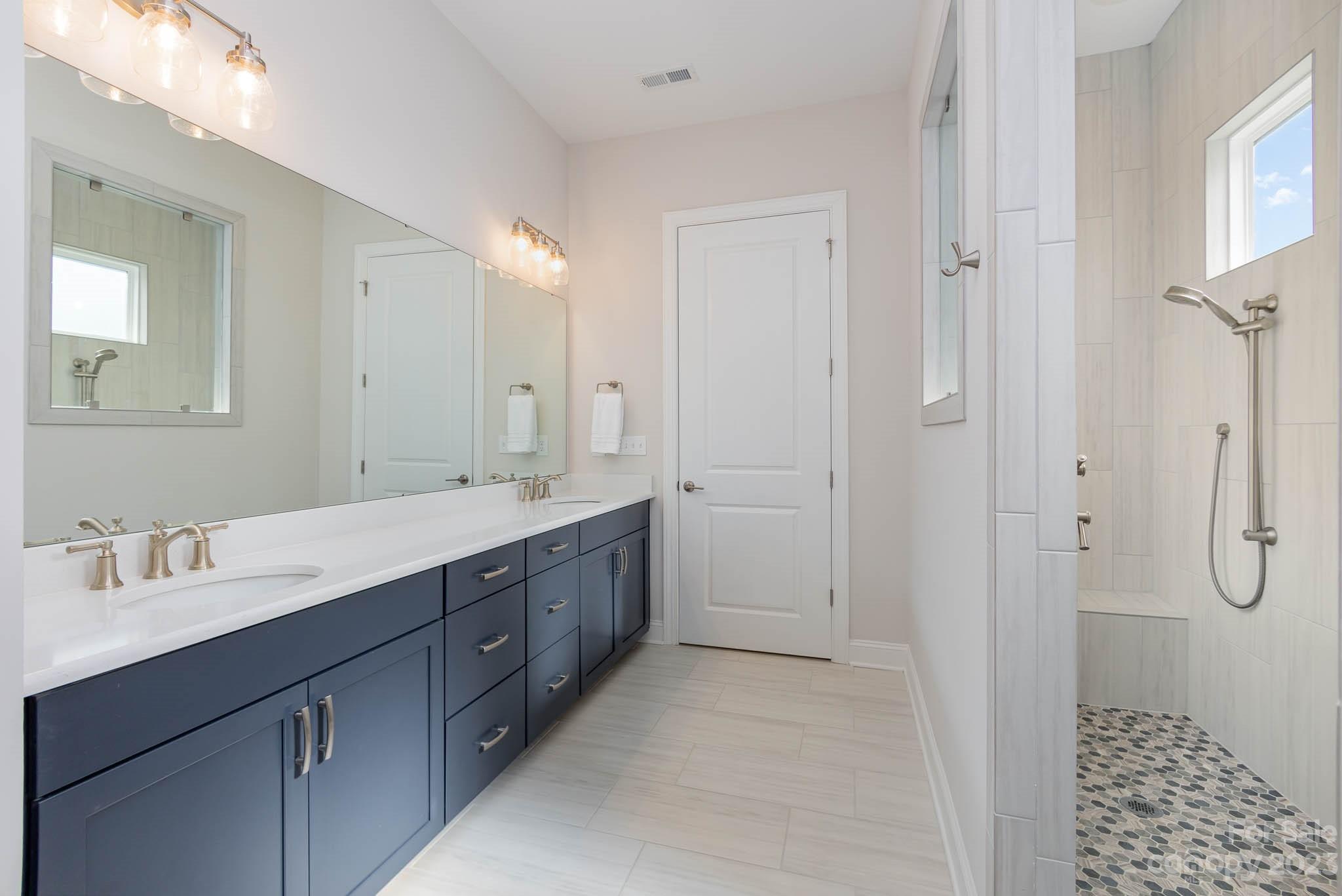17150 Sand Bank Road Charlotte, NC 28278 - Photo 15 of 32 a bathroom with a double vanity sink a mirror and a shower