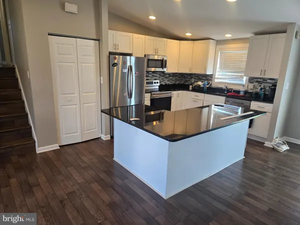 a kitchen with stainless steel appliances granite countertop a refrigerator a sink and wooden floors