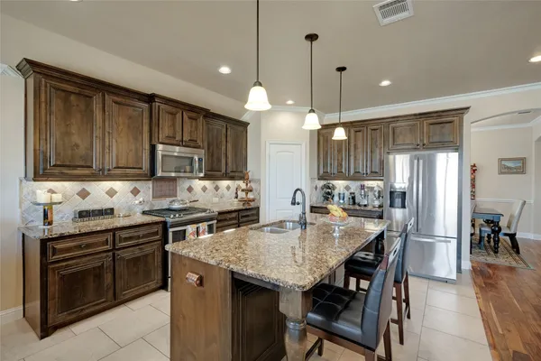 a kitchen with stainless steel appliances granite countertop a stove a sink a microwave a dining table and chairs