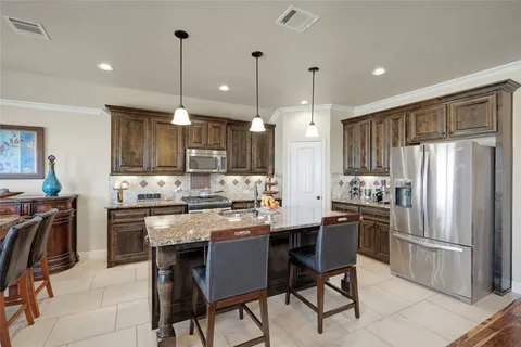 a kitchen with stainless steel appliances granite countertop a refrigerator a stove a sink a dining table and chairs