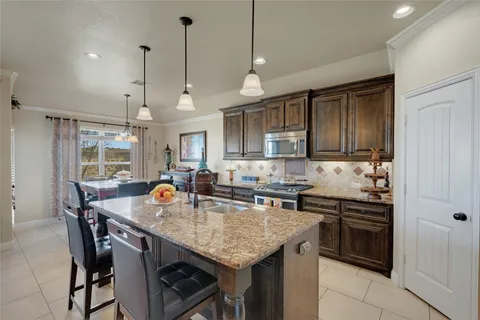 a kitchen with granite countertop a stove a sink a dining table and chairs