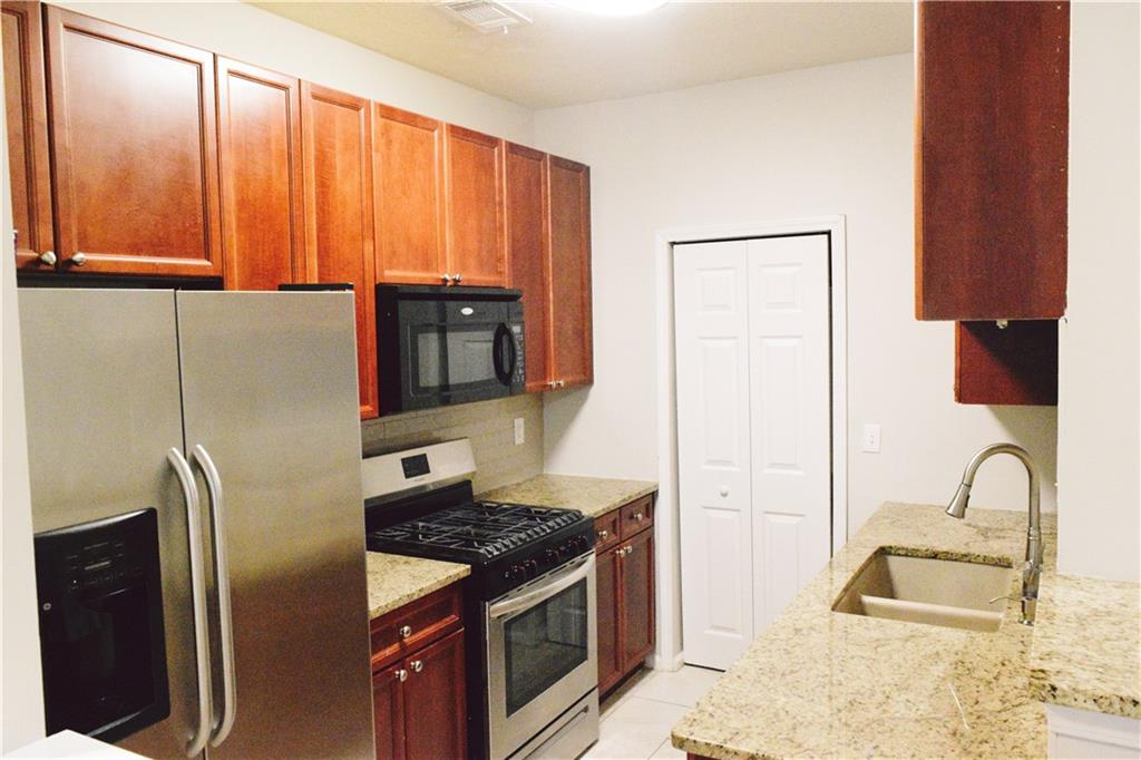 3500 Sweetwater Road, Unit 424 Duluth, GA 30096 - Photo 7 of 17 a kitchen with granite countertop a refrigerator stove and cabinets
