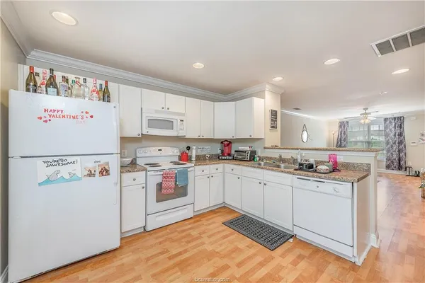 a kitchen with a stove a refrigerator and a white cabinets