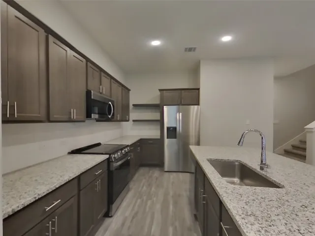 a kitchen with stainless steel appliances granite countertop a sink stove and refrigerator