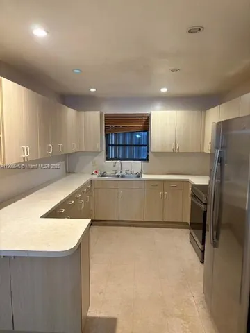 a kitchen with a sink a refrigerator a counter top space and cabinets