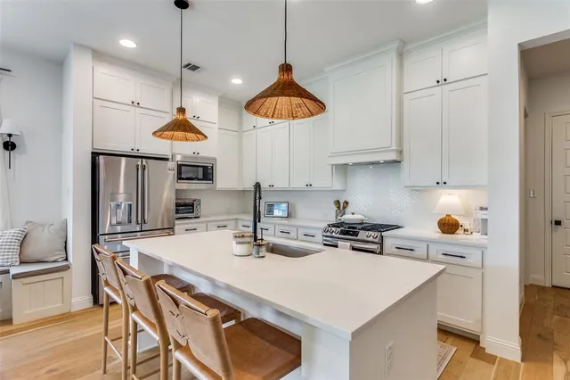a kitchen with stainless steel appliances granite countertop a sink a stove and chairs