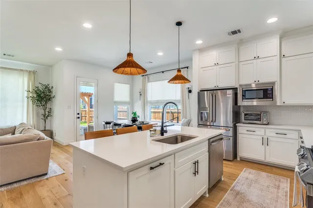 a kitchen with stainless steel appliances a sink a stove a refrigerator and white cabinets