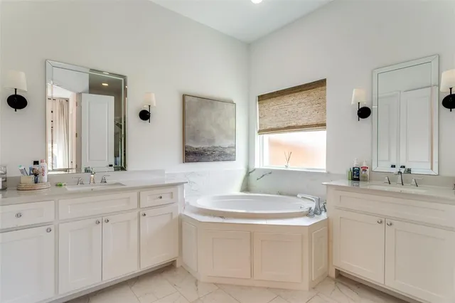 a bathroom with a bathtub sink double vanity and mirror