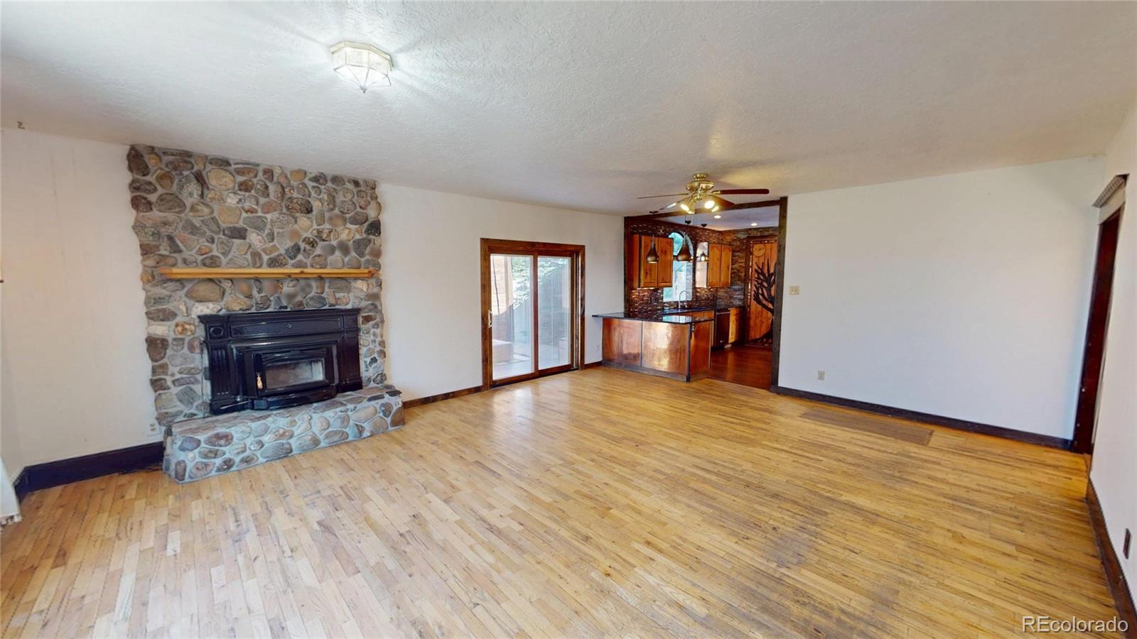 309 Main Street Romeo, CO 81148 - Photo 4 of 41 an empty room with wooden floor fireplace and windows
