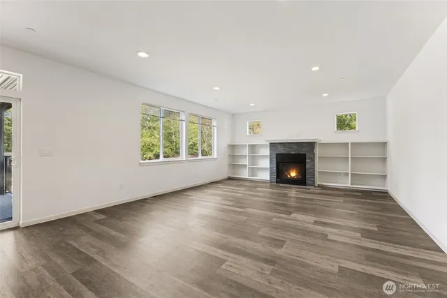 an empty room with wooden floor fireplace and windows