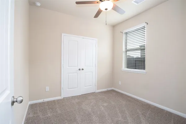 an empty room with a chandelier fan and windows