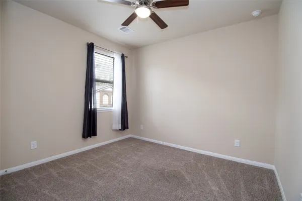 an empty room with windows and ceiling fan