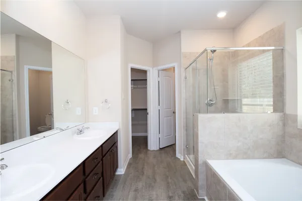 a spacious bathroom with a double vanity sink a mirror and a bathtub