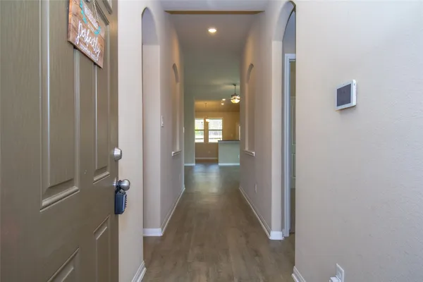 a view of a hallway with wooden floor and a bathroom