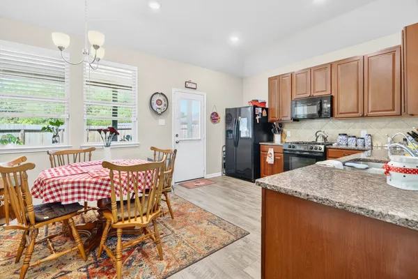 a kitchen with stainless steel appliances granite countertop a stove top oven a sink a dining table and chairs