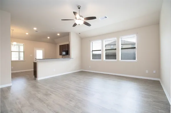 a view of an empty room with a window and wooden floor
