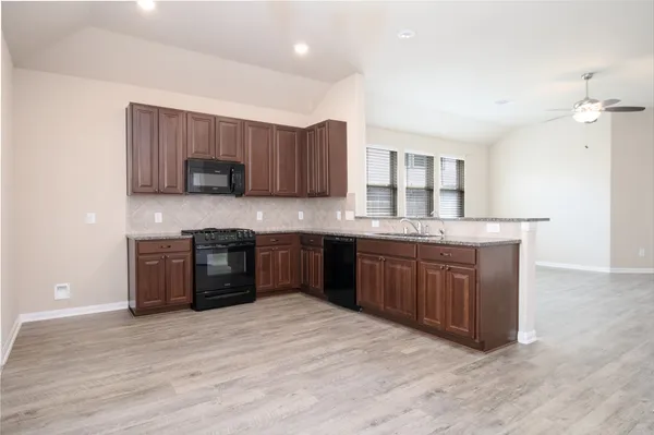 a kitchen with stainless steel appliances granite countertop a sink a stove a refrigerator cabinets and wooden floor