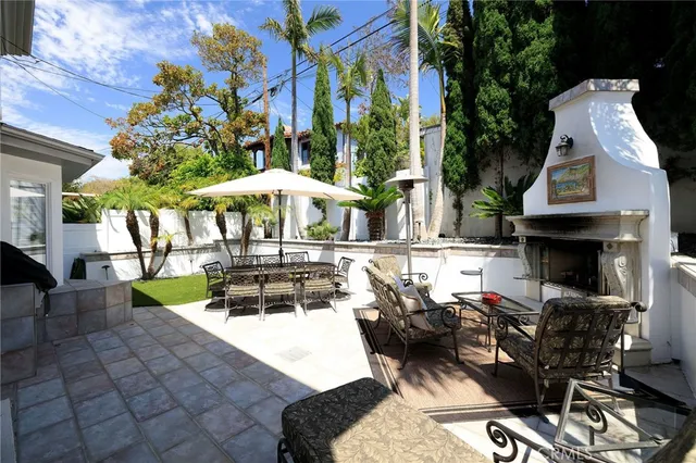 a view of a patio with table and chairs under an umbrella with a fire pit