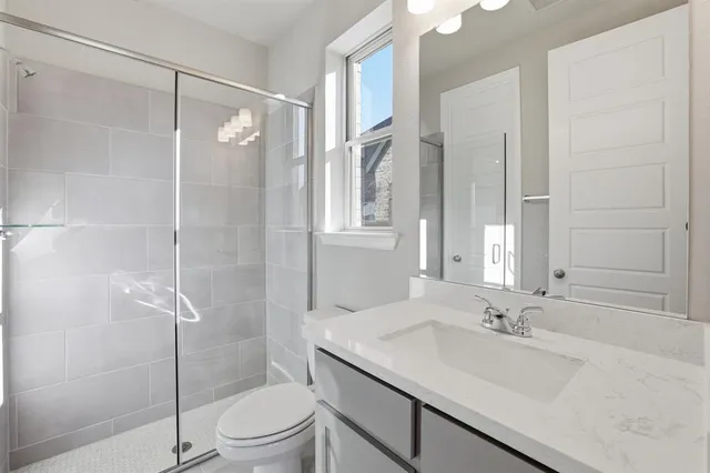a bathroom with a shower sink vanity mirror and toilet