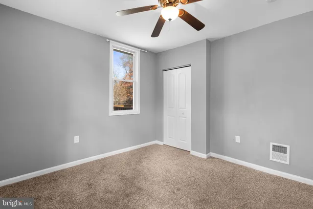 an empty room with closet and a chandelier fan