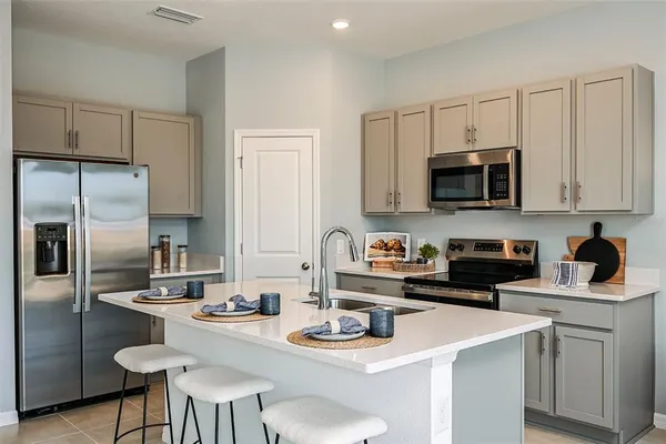 a kitchen with stainless steel appliances a sink a stove a refrigerator cabinets and a dining table