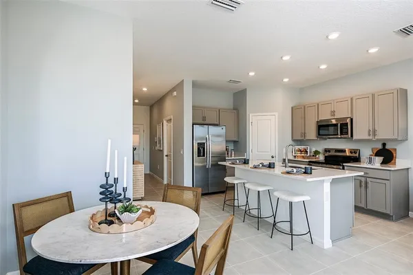 a kitchen with stainless steel appliances kitchen island granite countertop a sink a stove a dining table and chairs
