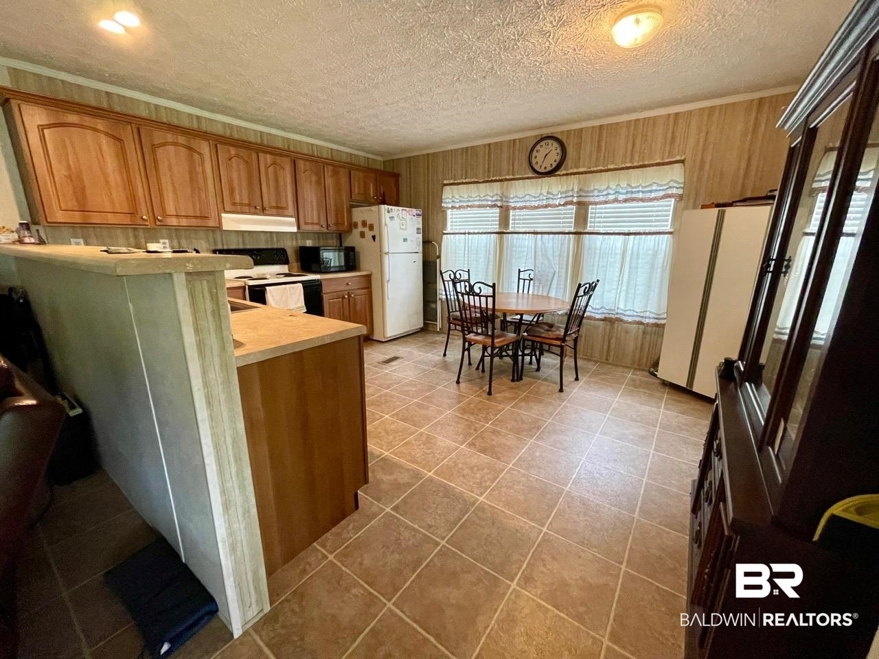 15338 Windbigler Drive Foley, AL 36535 - Photo 14 of 28 Kitchen with a textured ceiling, light tile patterned floors, white appliances, and wooden walls