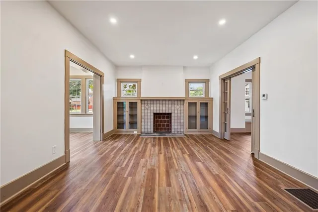 a view of an empty room with wooden floor fireplace and a window