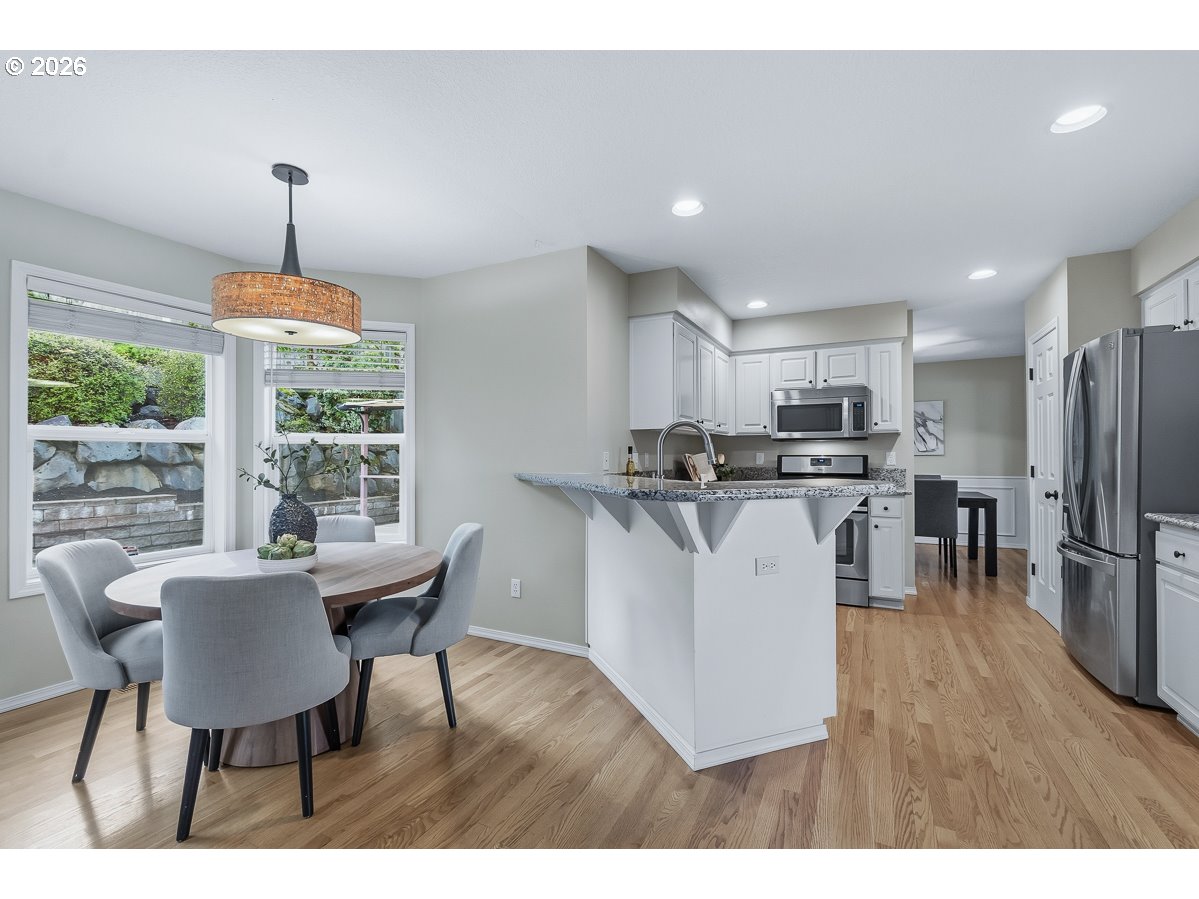 8361 Southwest 168th Avenue Beaverton, OR 97007 - Photo 15 of 31 a kitchen with stainless steel appliances a dining table chairs a refrigerator and cabinets
