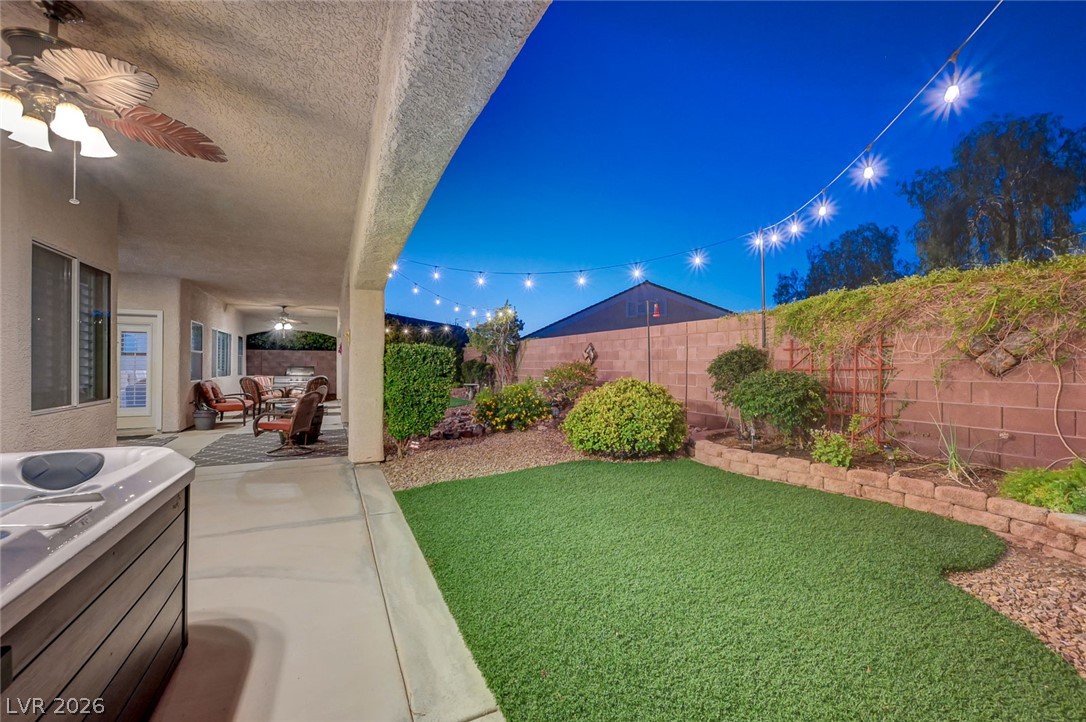 1604 Cattle Ranch Place Henderson, NV 89002 - Photo 85 of 99 Unwind in the tranquil backyard, featuring a covered patio, spa, and illuminated artificial turf.