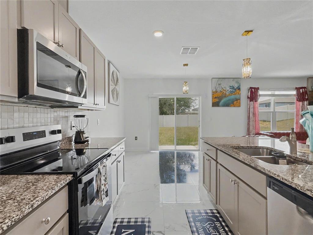 2085 Doe Run Drive Davenport, FL 33837 - Photo 13 of 44 a kitchen with stainless steel appliances granite countertop a sink stove and microwave
