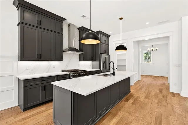 a kitchen with stainless steel appliances granite countertop a sink a stove and a wooden floor