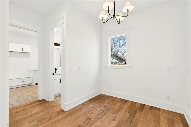 a view of a hallway with wooden floor and a bathroom