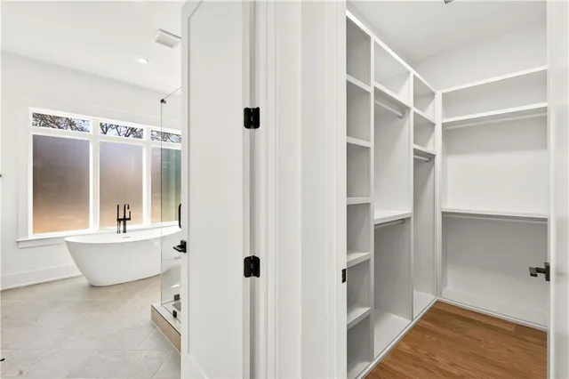 a view of an empty room with wooden floor fireplace and a window