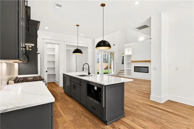 a kitchen with stainless steel appliances granite countertop a sink a stove and a wooden floor