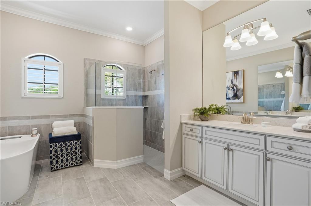 2235 Somerset Place Naples, FL 34120 - Photo 22 of 49 a spacious bathroom with a double vanity sink a mirror a bathtub and a window