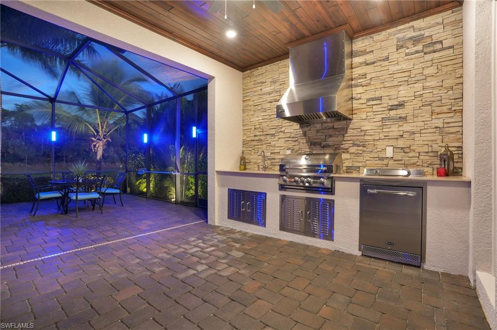 2235 Somerset Place Naples, FL 34120 - Photo 32 of 49 a kitchen with stainless steel appliances granite countertop a stove a sink and a wooden cabinets