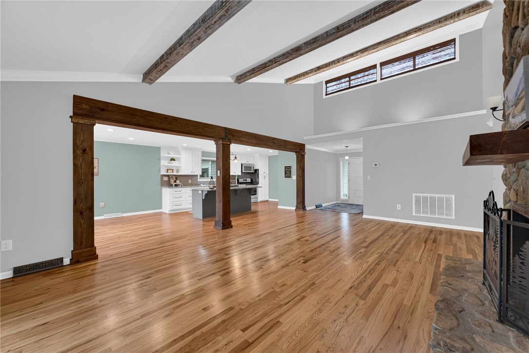 433 Latham Road Easley, SC 29640 - Photo 2 of 50 Exposed beams and rich wood flooring define this open-concept living space leading into a contemporary kitchen.