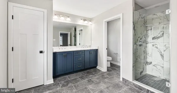 a bathroom with a granite countertop sink mirror and a shower