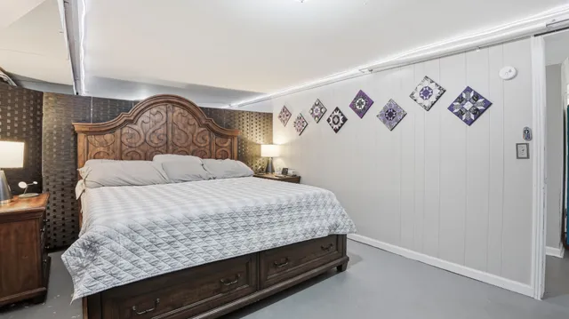 a bedroom with a bed and painting on the wall