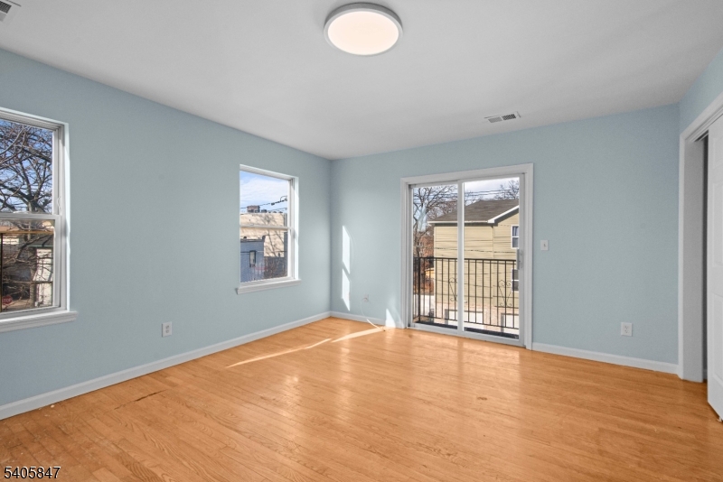 219 Clinton Place Newark, NJ 07112 - Photo 12 of 21 an empty room with wooden floor and windows
