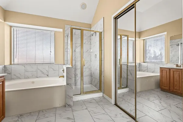 a spacious bathroom with a tub shower and windows