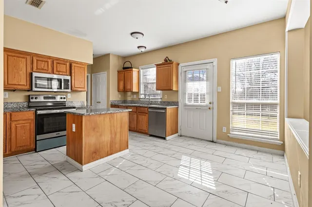 a kitchen with stainless steel appliances granite countertop a stove top oven a sink dishwasher and a refrigerator