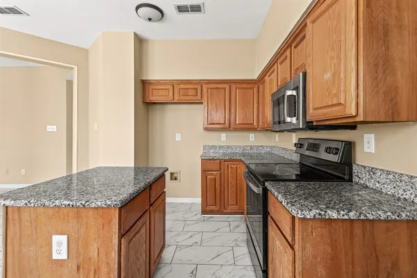 a kitchen with stainless steel appliances granite countertop a stove a sink and a microwave