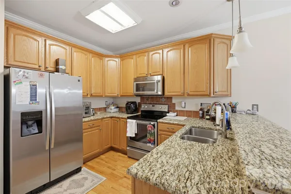 a kitchen with stainless steel appliances granite countertop a refrigerator a stove top oven a sink and dishwasher