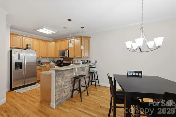 a kitchen with a dining table chairs stainless steel appliances and cabinets