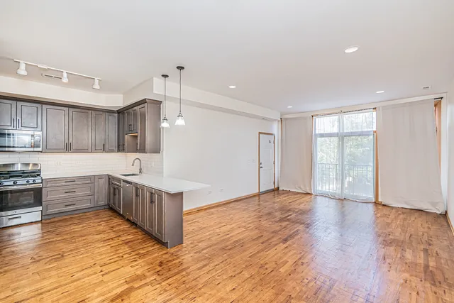 a kitchen with stainless steel appliances kitchen island wooden floors and white cabinets